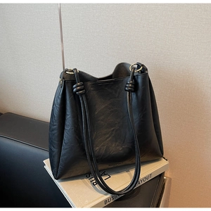 Detail of black tote bag with knot handle and gold hardware on vintage books