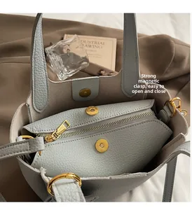 Detail of magnetic buckle closure and zipper pocket in gray-blue grain leather bag