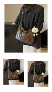 Detail of dark brown glossy leather tote bag with silver chain and white cloud charm