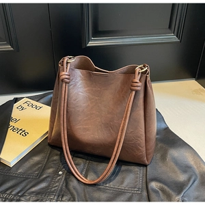 Detail of dark brown leather bucket bag featuring a unique double-knot handle design