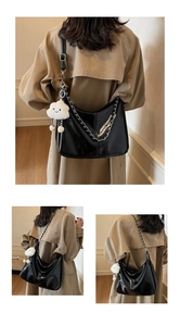 Detail view of black glossy tote bag with silver chain and white cloud charm accessory
