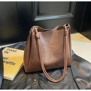 Detail of vintage dark brown tote bag with decorative knot straps and matte leather texture