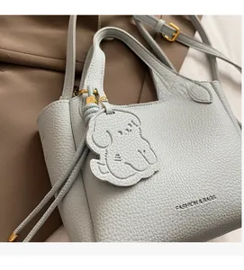 Close-up of light blue litchi grain leather bucket bag with cute dog charm and gold hardware