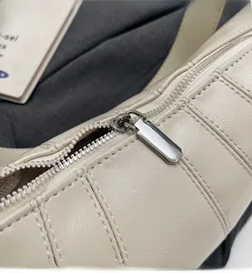 Detail of smooth silver metal zipper and vertical quilted texture on beige leather bag