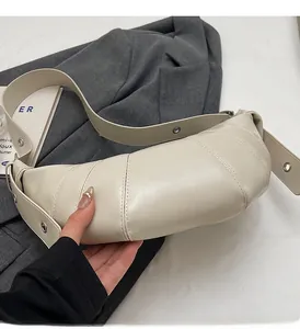 Detailed view of cream croissant bag featuring horizontal stitching and adjustable silver eyelets