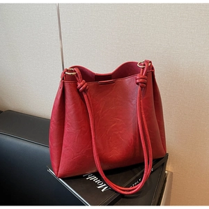 Detail of dark red vintage PU leather tote bag with golden rings and knot shoulder strap