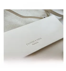 Close-up of ivory leather flap bag with embossed brand logo and fine texture