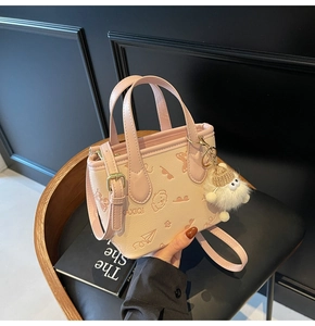 Detailed view of pink embossed bucket bag with cartoon patterns and plush charm
