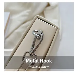 Detailed close-up of premium silver hardware lobster clasp on a beige crossbody bag