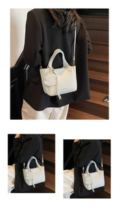 Detail view of white lychee leather bucket bag with cute dog charm and golden hardware