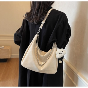 Detail view of cream hobo tote bag with silver chain and white plush cloud charm