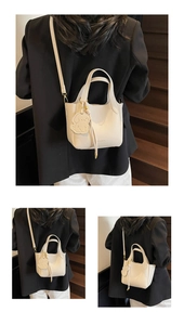 Detail of a beige lychee pattern leather bucket bag with dog charm and long strap