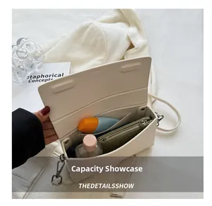 Detail view of cream leather crossbody bag interior with silver clasp and storage capacity