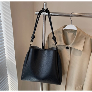 Detail of black tote bag with knot strap and fashion trend embossed lettering