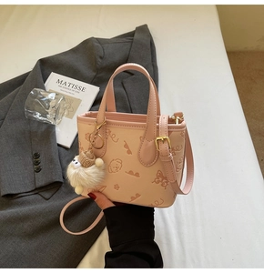 Detail van roze handtas met cartoon hond print, pluche hanger en gouden hardware