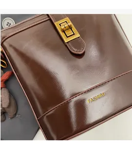 Dettaglio della borsa a secchiello in pelle cerata marrone con ciondolo a forma di orso
