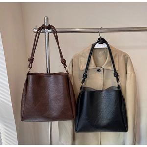 Detail of vintage tote bags in brown and black leather with stylish shoulder knot design