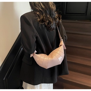 Detailed close-up of a pink croissant shoulder bag with pleats on a wooden staircase