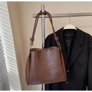 Close-up of brown leather bucket bag showing fine grain texture and embossed detail