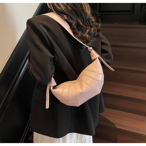 Detail of light pink croissant bag showing quilted leather texture and shoulder knot