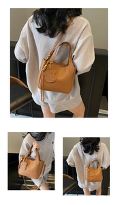 Detail of brown lychee leather bucket bag with cute dog charm and adjustable strap