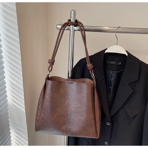 Close-up of vintage brown leather tote bag with unique knot detail and gold hardware