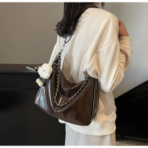 Close-up of a coffee brown faux leather tote bag with silver chain and plush bear charm