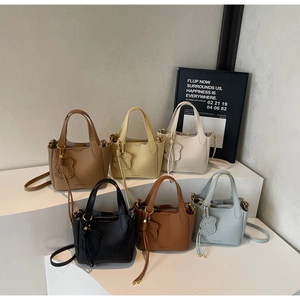 Close-up of minimalist leather tote bags in various colors featuring cute bear pendants