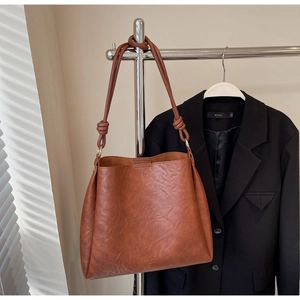 Brown vintage faux leather tote bag with knotted strap detail and elegant side texture