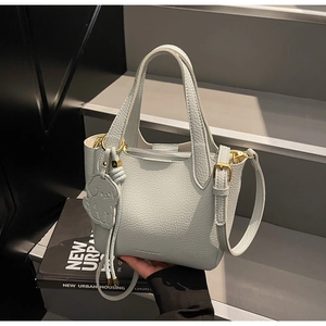 Detailed close-up of blue-grey pebble leather bag with gold hardware and dog charm