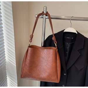 Detail of vintage brown leather bucket bag with decorative knotted strap and brand lettering
