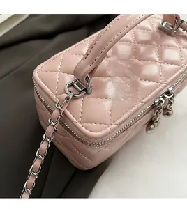 Macro detail of pink quilted leather bag with silver zipper and chain strap