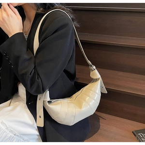 Detailed side view of a beige crescent croissant bag with geometric stitching and adjustable strap