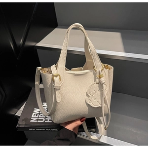 Close-up of lychee grain cream bucket bag with gold hardware and dog charm detail