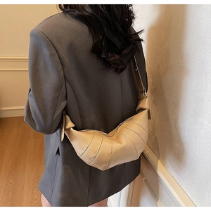 Detail of vintage beige croissant bag with pleated leather texture on grey suit