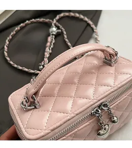 Close-up of pink quilted mini bag with silver chain strap and heart zipper detail