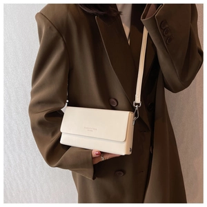 Detailed side view of a cream leather crossbody bag paired with an oversized brown blazer