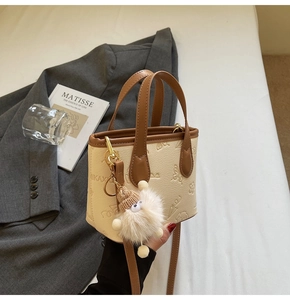 Detailed close-up of embossed floral patterns and plush charm on a beige mini handbag