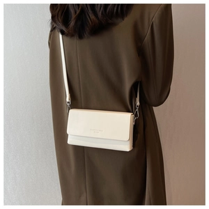 Minimalist cream white envelope crossbody bag worn over a dark brown blazer jacket