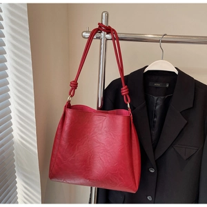 Detail of red oversized tote bag with knotted shoulder strap and gold hardware accents