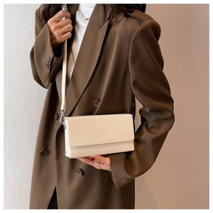 Detail of minimalist cream crossbody bag with textured leather and brand embossing