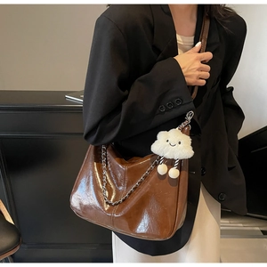 Polished brown tote bag with metal chain strap and white plush cloud charm accessory