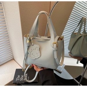 Detail of light blue lychee pattern bucket bag with cute dog pendant and gold metal hardware
