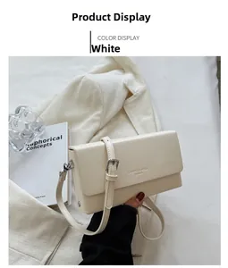 Detail of white PU leather crossbody bag with brand logo and silver metal buckle hardware