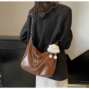 Brown soft leather tote bag detail with metal chain and white plush cloud pendant