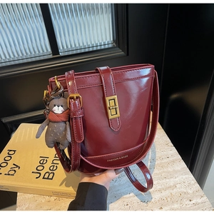 Dettaglio della borsa a secchiello bordeaux lucida con grazioso ciondolo a forma di orso