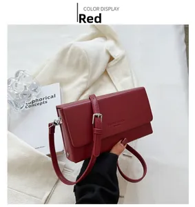 Detail of red faux leather crossbody bag with silver buckle on a white blazer