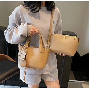 Detail of camel brown lychee leather tote bag set including a crossbody pouch and dog charm