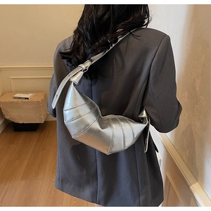 Silver metallic croissant bag detail with quilted texture and adjustable strap on model