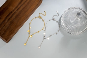 Detail of gold and silver heart tassel anklets with beads on a wooden display